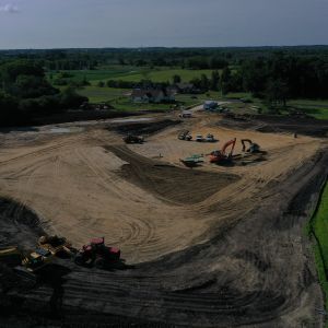 Backhoe loading a tractor with topsoil